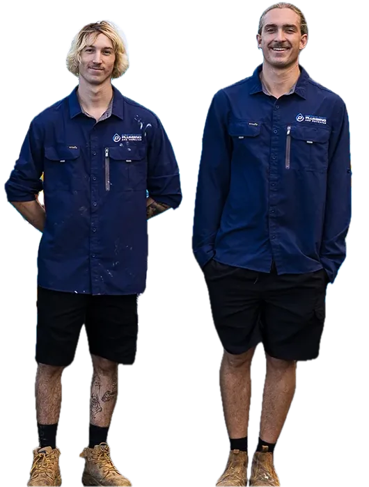 Two plumbers in navy work shirts, shorts and boots standing side by side and smiling